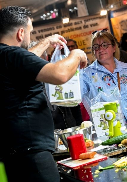 Démonstration de robot multifonction en cuisine avec découpe de légumes et remise de produits aux visiteurs. Made in Paris