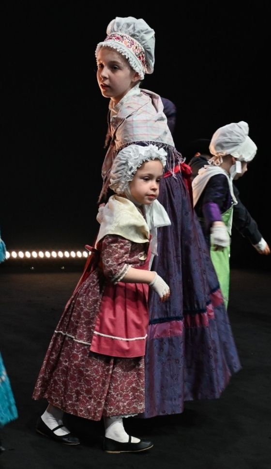 Des enfants portent des costumes traditionnels lors d’une représentation, mettant en valeur la transmission culturelle.