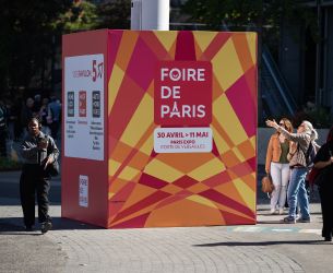 Cube publicitaire coloré de Foire de Paris installé en extérieur avec des visiteurs autour.