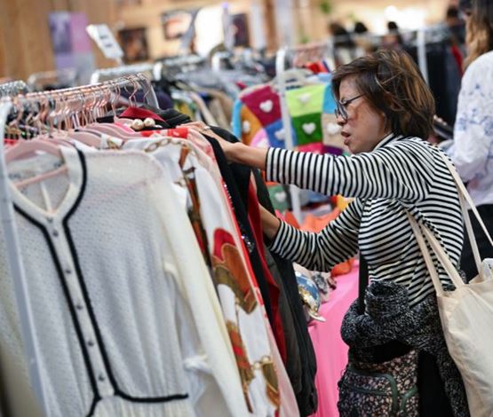 femme regardant des vetements de seconde main sur des portants