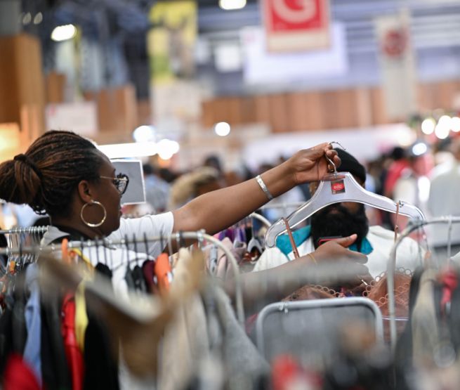 femme regardant des vetements de seconde main sur des portants