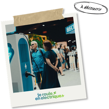 Couple observant une borne de recharge pour voiture électrique lors d’un salon dédié à la mobilité durable.