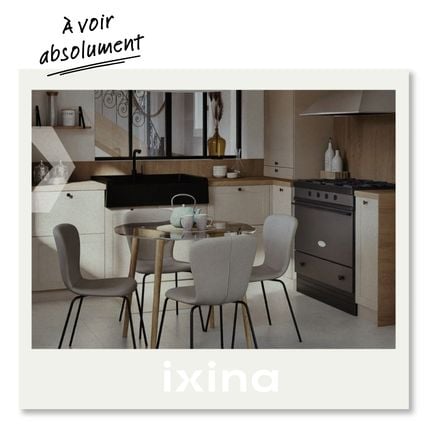 Cuisine moderne avec table ronde en verre et quatre chaises, suspension blanche, evier noir et cuisiniere inox dans un interieur lumineux.