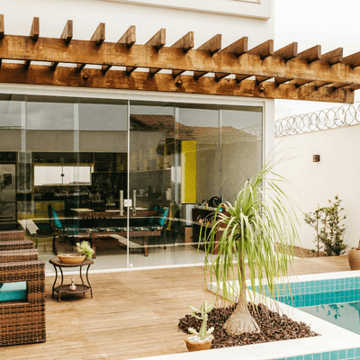 Maison moderne avec terrasse en bois, pergola, piscine et grande baie vitrée donnant sur le salon.
