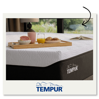 Photo d'un lit avec un matelas Tempur. Sur le lit, un plateau avec des fruits, du jus et un livre. Un cadre agréable dans une chambre lumineuse avec des fenêtres ouvertes. Logo Tempur visible.