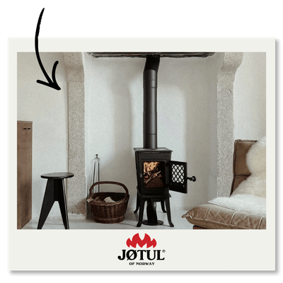 Photo d’un salon intérieur avec un poêle à bois Jøtul au centre. L'appareil est posé dans un cadre élégant, entouré de murs en pierre et d'un mobilier cosy. Logo Jøtul en bas.