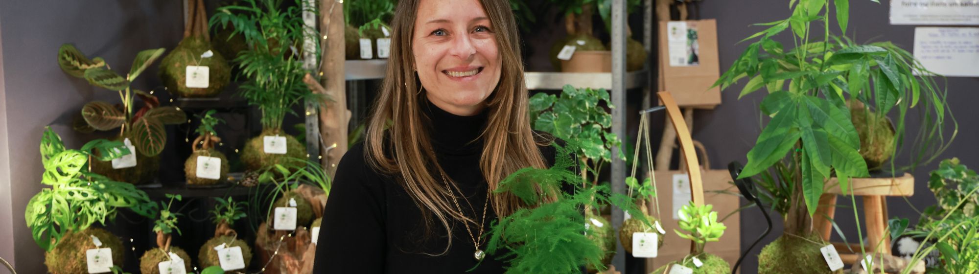 portrait d'une exposante devant son stand de plante artisanale