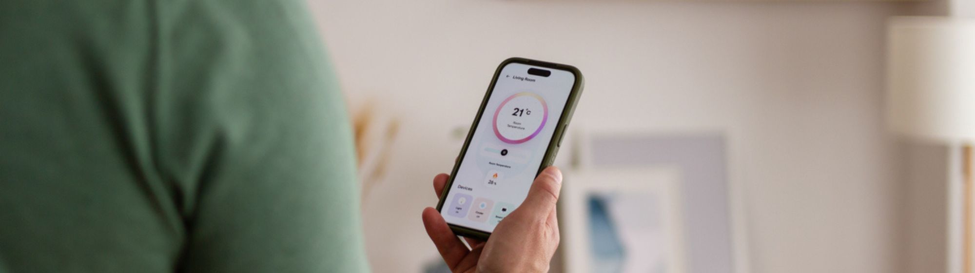 Personne utilisant un smartphone connecté pour contrôler un appareil dans un intérieur moderne.